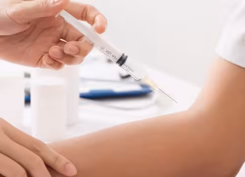A close-up of a person's arm receiving an injection from a healthcare worker holding a syringe.
