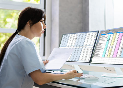 Woman in scrubs sitting in front of computer screens