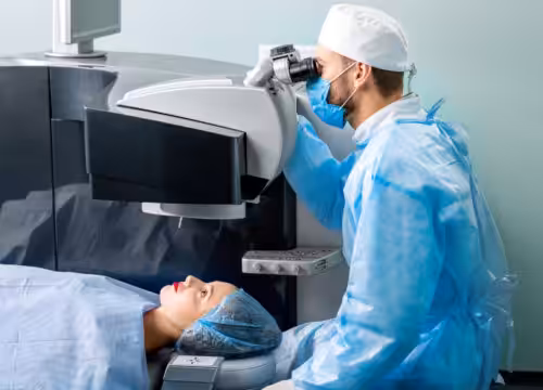 Eye surgeon operating woman with laser vision correction machine in the operating room.