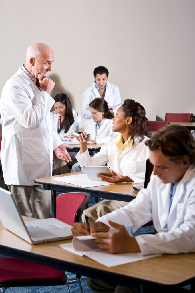 Professor with medical students wearing lab coats in classroom