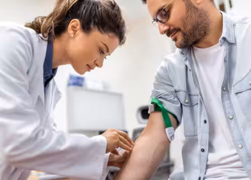 Phlebotomist drawing blood from patient's arm during clinical procedure